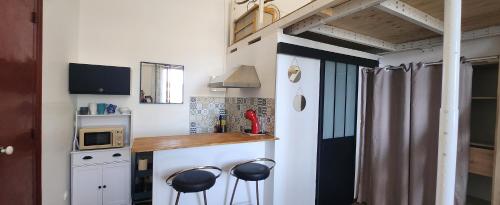 une petite cuisine avec deux tabourets au bar dans une petite maison dans l'établissement Studio Xana vue Adour, à Bayonne