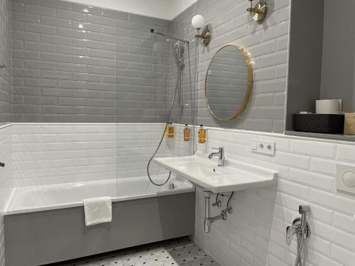 a white bathroom with a sink and a shower at Aparthotel Amella in Rīga