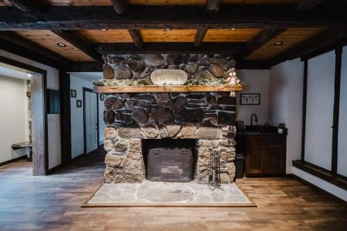 a stone fireplace in a living room with wooden ceilings at 13 Beds, 17 Guests with Hot tub only 15Mins to Sunday River in Newry