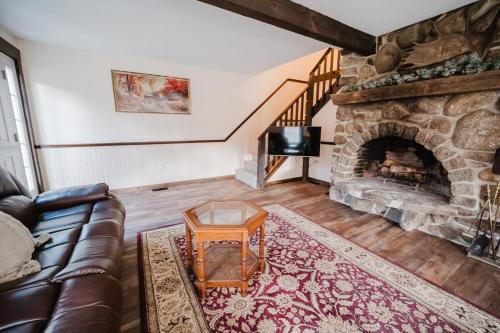 a living room with a couch and a stone fireplace at 13 Beds, 17 Guests with Hot tub only 15Mins to Sunday River in Newry