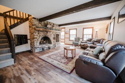 a living room with a couch and a stone fireplace at 13 Beds, 17 Guests with Hot tub only 15Mins to Sunday River in Newry