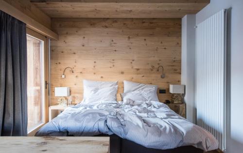 a bedroom with a bed with a wooden wall at La Genzianella Bormio in Bormio