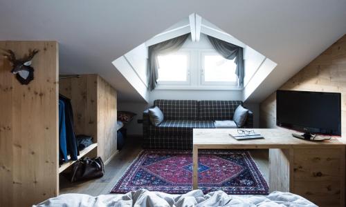 a room with a bed and a desk and a window at La Genzianella Bormio in Bormio