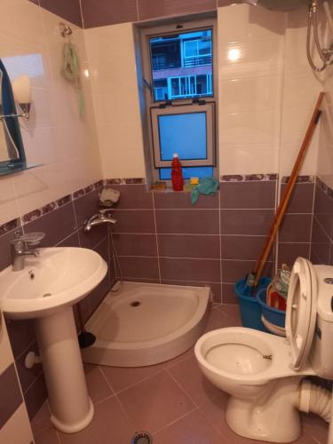 un bagno con lavandino, WC e finestra di Zana's Apartment a Pogradec