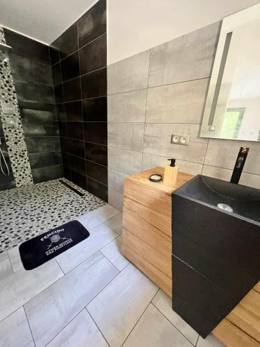 La salle de bains est pourvue d'une baignoire noire et d'un lavabo. dans l'établissement cozy Home stay, à Mimet