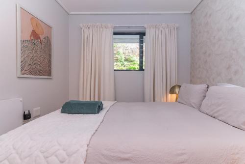 a bedroom with a large white bed and a window at Modern One Bedroom Wavescapes Apartment Muizenberg in Muizenberg