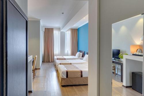 a hotel room with two beds and a desk at Hotel Mevora in Tbilisi City