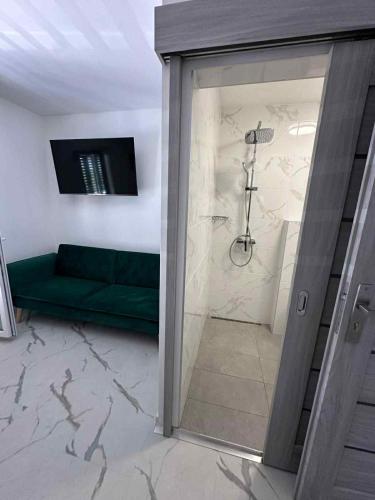 a bathroom with a green couch and a shower at Apartmány Zuzana in Primošten