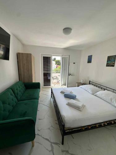 a bedroom with a large bed and a green couch at Apartmány Zuzana in Primošten