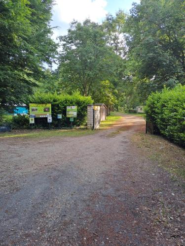 un chemin de terre avec des buissons et des arbres en arrière-plan dans l'établissement Camping Paradis Nature, à Ivoy-le-Pré