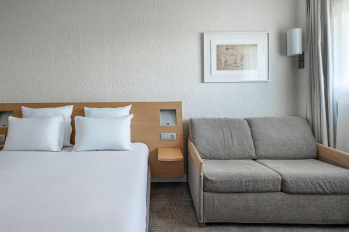 a hotel room with a bed and a couch at Novotel Poissy Orgeval in Orgeval