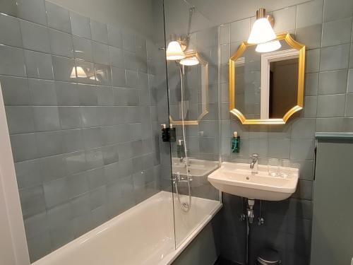 a bathroom with a sink and a tub and a mirror at Aparthotel Amella in Rīga