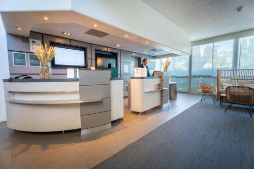an office with a man standing at a counter at Novotel Poissy Orgeval in Orgeval