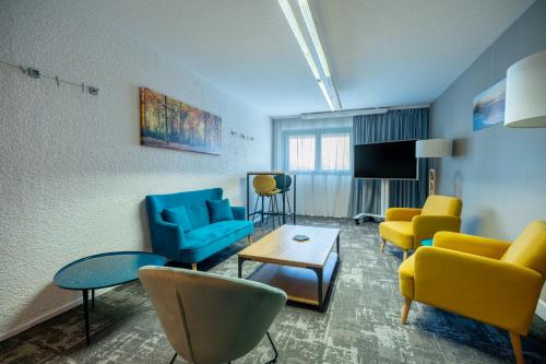 a waiting room with blue and yellow chairs and a table at Novotel Poissy Orgeval in Orgeval