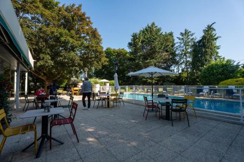 a patio with tables and chairs next to a pool at Novotel Poissy Orgeval in Orgeval