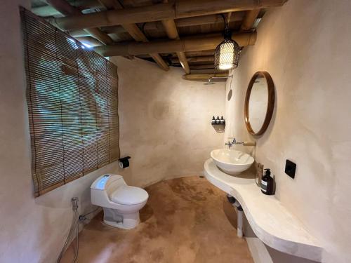 a bathroom with a toilet and a sink and a mirror at Alpaca Lodge in Tanah Lot