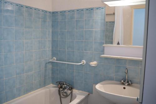 La salle de bains est pourvue de carrelage bleu, d'une baignoire et d'un lavabo. dans l'établissement Les Cigalines Appartement avec Piscine, à Cavalaire-sur-Mer