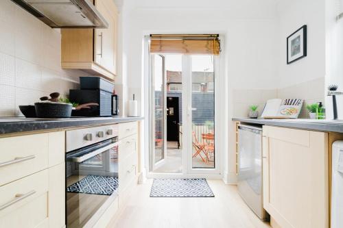 a kitchen with white cabinets and a door to a patio at Modern 2 Bed Apt with Roof Terrace - Ecclesall Rd - Now Hosted by StayHostSave in Sheffield