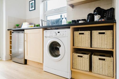 a laundry room with a washing machine and baskets at Modern 2 Bed Apt with Roof Terrace - Ecclesall Rd - Now Hosted by StayHostSave in Sheffield