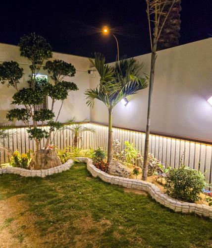 a fence with palm trees in a yard at night at The White Suites in Karachi