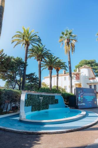 une piscine dans un parc planté de palmiers dans l'établissement Campus Santa Maria, à Cannes