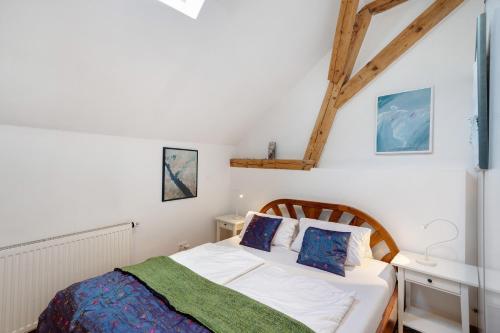 a bedroom with a bed with white sheets and blue pillows at Atelierblick im Winzerort in Oberbergen
