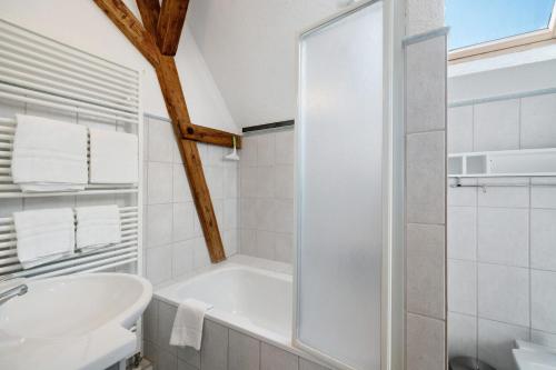 a white bathroom with a tub and a sink at Atelierblick im Winzerort in Oberbergen