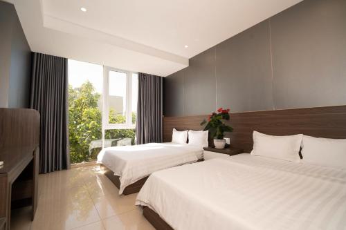 a hotel room with two beds and a window at Ngoc Se Hotel in Pleiku