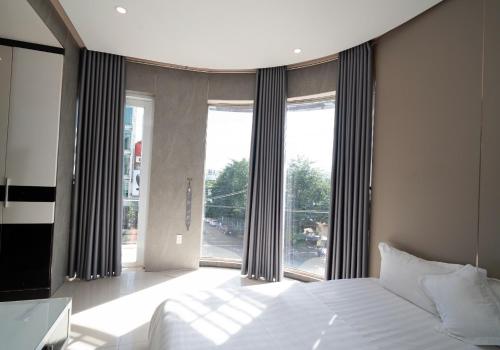 a bedroom with a bed and a large window at Ngoc Se Hotel in Pleiku