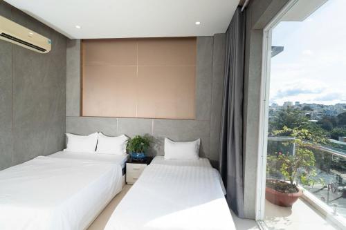 two beds in a room with a window at Ngoc Se Hotel in Pleiku