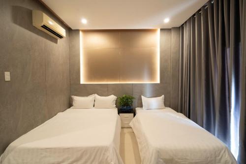 two beds in a hotel room with white sheets at Ngoc Se Hotel in Pleiku