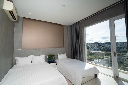 two beds in a room with a large window at Ngoc Se Hotel in Pleiku
