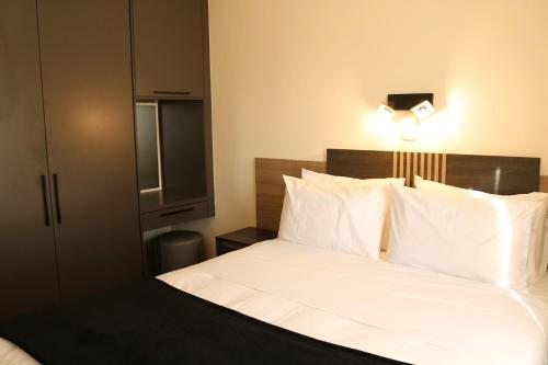 a bedroom with a bed with white sheets and pillows at Melrose Corner Self-Catering Hotel Apartments in Johannesburg