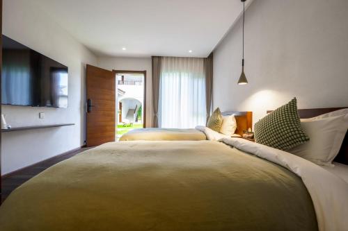 two beds in a hotel room with a tv at 大理沙溪云喜七月精品客栈 Shaxi Ancient Town Yunxi Qiyue Guesthouse in Jianchuan