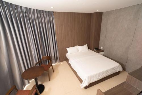a bedroom with a bed and a table and a chair at Ngoc Se Hotel in Pleiku