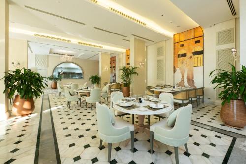 a restaurant with white tables and chairs and plants at Cleopatra Sidi Heneish in Marsa Matruh
