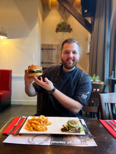 a man is holding a sandwich and french fries at Herberg de Brabantse Kluis in Aarle-Rixtel