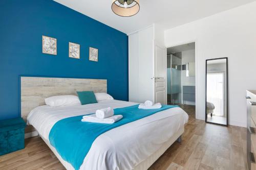 - une chambre bleue avec un grand lit et des serviettes dans l'établissement Le Retz de Jardin - Appartement calme avec parking, à Saint-Léger-les-Vignes