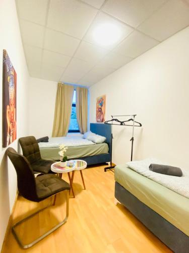 a bedroom with two beds and a chair and a table at Sweet 3-Bedroom shared Apartment in a Quiet Neighborhood in Vienna