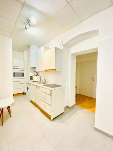 an empty kitchen with white cabinets and a table at Sweet 3-Bedroom shared Apartment in a Quiet Neighborhood in Vienna