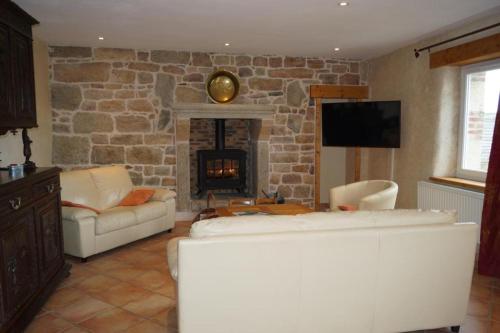 - un salon avec un canapé et une cheminée en pierre dans l'établissement Ti Bras Gite de Saint Guénolé, à Trévou-Tréguignec