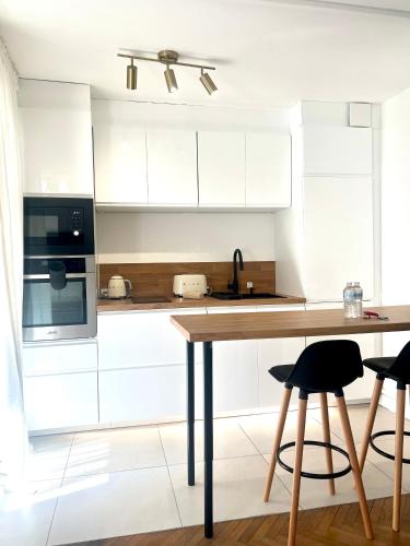 une cuisine avec des armoires blanches et une table en bois dans l'établissement Lyon Suite Cosy - Climatisé - Appartement T2 - Proche Parc Tête d'Or, à Villeurbanne