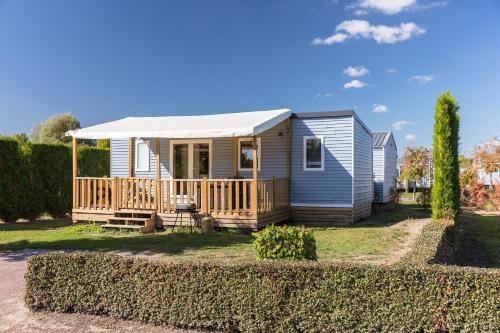 a tiny house with a porch and a deck at Camping La Croix du Vieux Pont in Berny-Rivière