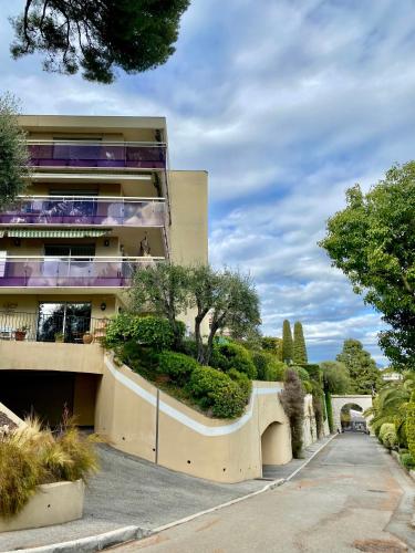 a building on a street with bushes and trees at NICE luxury residence, Garden level with sea view and swimming pool, 2bedroom apartment of approximately 85 square meter and private garden in Nice