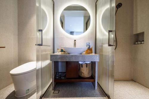 a bathroom with a sink and a toilet and a mirror at 大理沙溪云喜七月精品客栈 Shaxi Ancient Town Yunxi Qiyue Guesthouse in Jianchuan