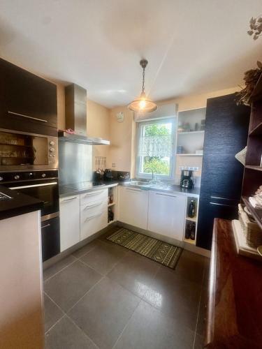 une grande cuisine avec des armoires blanches et une fenêtre dans l'établissement Apartment with sea view and access, à LʼÎle-Rousse