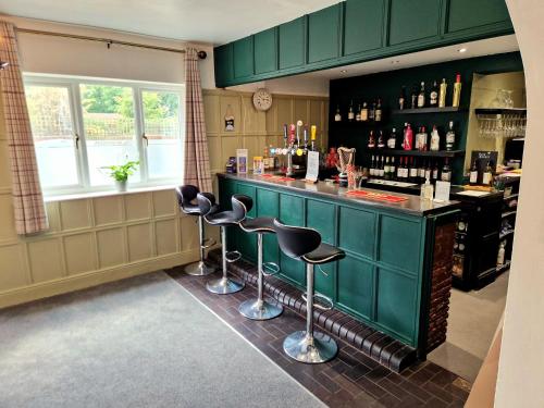 a bar with green cabinets and stools in a room at The Kensington in Great Yarmouth