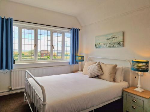 a bedroom with a white bed and two windows at The Kensington in Great Yarmouth