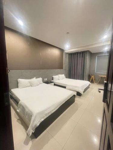 two beds in a hotel room with white sheets at Ngoc Se Hotel in Pleiku