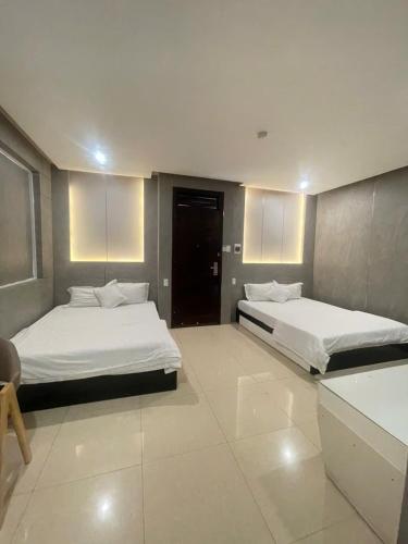 two beds in a large room with white floors at Ngoc Se Hotel in Pleiku